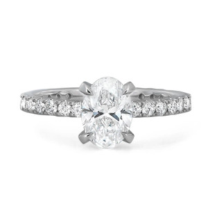 An image of a Rachel Koen brand engagement ring for women, featuring a prominent oval-cut lab grown diamond set in a four-prong setting at the center, flanked by round-cut lab grown diamonds along the band. The ring is captured from a front-facing angle that highlights the sparkle and structure of the central diamond, with the band slightly angled to show the encrusted diamonds' detail. The photo is taken from a close, yet fully revealing distance, presenting a clear view of the ring's design and craftsmanship against a white background.