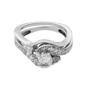 An image of a Rachel Koen women's two piece set engagement ring with diamonds, showcased in a close-up view against a white background. The ring features a polished white gold band with a twisted design, angled slightly to the left of the frame, allowing a clear view of the intricate setting. The diamonds are embedded along the intertwining strands and at the center, with the largest stone prominently displayed at the intersection of the bands. The craftsmanship is highlighted by the varying sizes of the stones and the reflective metallic surface.