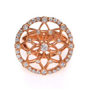 An image of a Luca Carati women's cocktail ring with diamonds, showcasing an intricate rose gold band with a filigree pattern. The ring is photographed from a top-down angle, capturing the circular design centered with a large diamond and surrounded by smaller diamonds, all set against a white background. The view is close-up, highlighting the sparkle and details of the diamonds and the craftsmanship of the band.