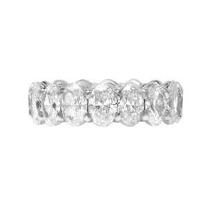 An image of a Rachel Koen women's eternity ring with diamonds, displayed frontally at a close distance with a direct angle, showcasing a continuous band of large, oval-cut diamonds set in a polished platinum metal, creating a luxurious and sparkling appearance with high clarity and brilliance against a white background.