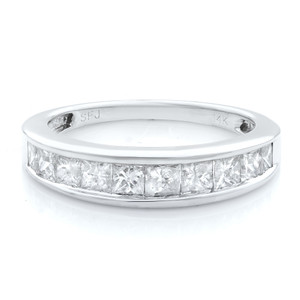 An image of a Rachel Koen women's wedding ring with diamonds, presented in a close-up view. The ring, centered and in sharp focus, features a continuous row of large, princess-cut diamonds set in a channel around the band. The sleek, polished white gold band is visible at the top and bottom of the diamonds, with the "14K" hallmark faintly visible on the side. The ring is photographed at a slight angle, emphasizing the sparkle of the diamonds against the white background.