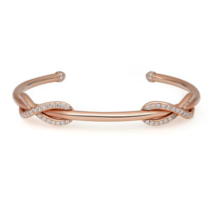 An image of a Tiffany women's open bracelet with diamonds, displayed in a medium close-up view against a white background. The rose gold bracelet features a twisted design with two bands intersecting at both sides, where a delicate ribbon of small, sparkling diamonds enhances the piece's elegance. The bracelet's ends are capped with pave set diamonds, and the item is positioned diagonally in the frame, providing a clear view of its intricate details and craftsmanship.