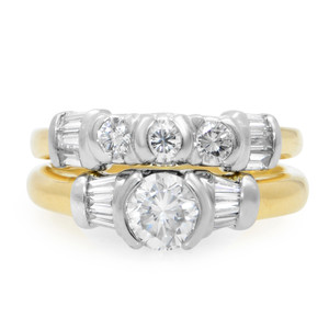 An image of a Rachel Koen women's engagement ring with wedding band in diamonds, displayed frontally at a close distance with a slight angle to show the ring's depth. The ring features a large central round cut diamond with baguette cut diamonds on both sides set in a white gold and yellow gold band, flanked by smaller diamonds on the wedding band. The band transitions to yellow gold as it encircles the finger, emphasizing the two-tone design.