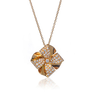 An image of a new Luca Carati women's necklace with diamonds, showcasing a gold pendant with a pinwheel-like design adorned with round cut diamonds, hanging from a yellow gold chain. The pendant is centered and presented at a direct, front-facing angle with a slight reflection visible below, indicating it is on a reflective surface. The pendant and chain are shown in close-up, with a white background to highlight the intricate details and sparkling gems.
