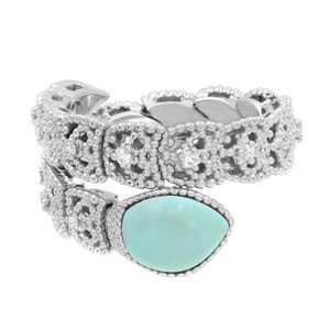 An image of a Piero Milano women's cockatil ring with diamonds and turquoise. The ring is displayed at a slight angle, with the top of the ring facing the camera, providing a clear view of the gemstones' settings. The main focus is a large, pear-shaped turquoise gemstone, which is bezel-set and positioned at the bottom right in the foreground. Surrounding the turquoise stone, the band is intricately designed with clusters of small diamonds, enhancing its sparkle. The ring's detailed craftsmanship is visible, with the white gold metalwork's texture and shine captured in the lighting. The background is a neutral white, ensuring the jewelry piece stands out, and the image is taken from a close distance to show the ring's details.