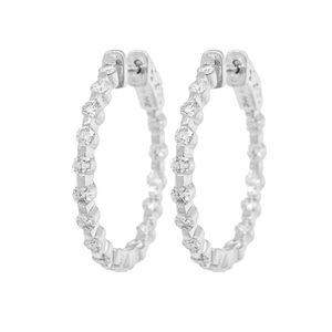 An image of a pair of Rachel Koen women's hoop earrings with diamonds, presented frontally and centered in the frame. The earrings are displayed against a white background, showcasing their circular shape and the intricate placement of the diamonds along their circumference. Each earring features multiple round-cut diamonds, evenly spaced and set in a polished white gold. The photo is taken from a straight-on angle at a close distance, providing a clear view of the earrings' design and the sparkling diamonds.