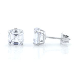 An image of a pair of Rachel Koen brand stud earrings designed for women, featuring sparkling cubic zirkonia. The earrings are positioned on a reflective surface with one earring facing front showing the asher-cut cubic zirconia face, and the other turned sideways to a 90-degree angle revealing the profile and post-back closure. Both earrings are in close proximity to each other, and the image is taken from a close distance, providing a clear view of the diamonds and the earring setting.