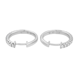 An image of a pair of Rachel Koen women's hoop earrings with diamonds. The earrings are presented in a frontal view against a white background. They are hoop-style with a row of sparkling round cut diamonds set in the front half and polished white gold at the back. The earrings are positioned parallel to each other, with a slight separation, and are shown at a close distance for a clear view of the details. The angle is head-on, allowing for a symmetrical display of the earrings' design.