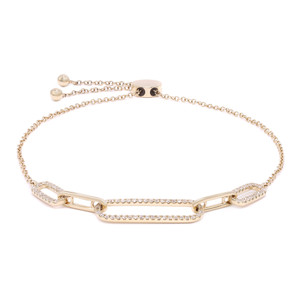 An image of a Rachel Koen women's paper clip link bolo bracelet with diamonds, displayed on a white background. The bracelet is positioned centrally and horizontally, with a slight tilt to the right side, giving a three-dimensional perspective. It features a delicate yellow gold chain with evenly spaced diamond embellishments and a larger, oblong gold link encrusted with diamonds at the center. The clasp and adjustable chain can be seen to the left, indicating the bracelet's versatility in size. The image is taken from a close distance, providing a clear view of the intricate details and the sparkle of the diamonds.