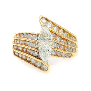 An image of a Rachel Koen women's engagement ring with diamonds, displayed at a close frontal angle showcasing the intricate design. The ring features a two pear-shaped diamond center stone, prong-set and elevated slightly above the band giving an illusion of one marquise cut diamond. The band itself is adorned with multiple rows of smaller round-cut diamonds set in a polished yellow gold, creating a radiant and luxurious appearance with a clear view of the sparkling facets. The image captures the ring's details and the brilliance of the gemstones with the background out of focus to emphasize the product.