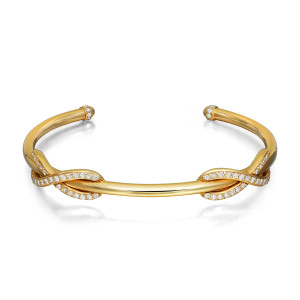 An image of a Tiffany & Co cuff bracelet designed for women, featuring a sleek 18k yellow gold band adorned with round brilliant cut diamonds. The bracelet is positioned horizontally at a slight angle, showcasing the intricate diamond-studded loops near the center. The image is taken from a close-up perspective, highlighting the luxurious details and craftsmanship. Excellent pre-owned condition. 