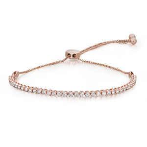 An image of a Rachel Koen women's bracelet with lab grown diamonds. The bracelet is displayed in a straight line at a slight angle, allowing the viewer to see the full length of the piece. It features a series of sparkling round-cut lab grown diamonds set in a rose gold bracelet, with a slider clasp for adjustment visible at the top center. The bracelet is shown against a white background, positioned to give a clear view of the diamonds' brilliance and the delicate metalwork. The image is taken from a close-to-medium distance, emphasizing the jewelry's elegance and detail.