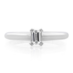 An image of a Rachel Koen brand engagement ring with diamonds, intended for women. The ring features a prominent emerald-cut center diamond, prong-set and displayed frontally. The band appears smooth and polished, without additional stones, narrowing slightly as it approaches the central setting. The view is a close-up, head-on perspective, showing the ring's profile and the reflective facets of the diamond. The background is pure white, emphasizing the ring's detail and the diamond's clarity.