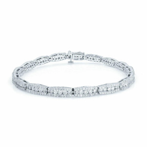 An image of a Rachel Koen women's tennis bracelet with diamonds, shown from a front-facing angle. The bracelet is displayed against a white background and is positioned horizontally across the frame. It features multiple rows of sparkling diamonds, meticulously set within a polished white gold band. The clasp is visible and located at the top center of the bracelet, indicating it is designed to be worn with the clasp at the underside of the wrist. The photograph is taken from a close distance, capturing the intricate details and reflections of the diamonds and metalwork.