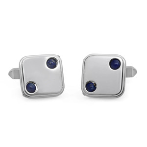 An image of men's Baraka cufflinks positioned side by side. They are square with rounded edges, featuring two small, round blue Lapis Lazuli stones on each cufflink. The cufflinks are shot from a slight overhead angle and are positioned at a close distance, showcasing their metallic sheen and minimalist design.