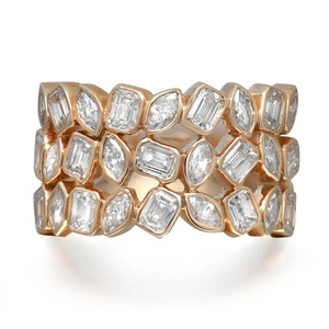 An image of a women's ring by Rachel Koen, showcasing a multi layered design adorned with multiple shaped diamonds. The ring is positioned slightly tilted, allowing a clear view of its intricate arrangement of emerald and marquise-cut diamonds set in a yellow gold band. The photograph is taken from a close angle, highlighting the brilliance and craftsmanship of the piece.