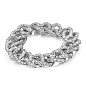 An image of a Damiani bracelet with diamonds, featuring a close-up view from a slightly elevated angle. The bracelet is displayed in a circular position, showcasing its intricate, Cuban link chain design encrusted with numerous sparkling diamonds in white gold. The focus is on the detailed craftsmanship, highlighting the luxurious and elegant appearance of the unisex adult accessory.