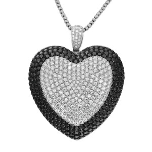 An image of a heart-shaped necklace pendant adorned with white and black diamonds. The pendant is centered and angled slightly forward, showcasing the intricate pattern of diamonds in white gold. The chain is visible at the top, emphasizing the pendant's elegance. The photo is taken close-up, highlighting the sparkle and detail of the diamonds.