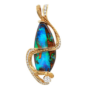 An image of a Rachel Koen unisex pendant featuring a central marquise-shaped boulder opal with vibrant blue and green hues interspersed with brown. The gemstone is elegantly wrapped in a flowing yellow gold setting adorned with small diamonds. A larger diamond is positioned at the base of the pendant. The pendant is viewed from a frontal angle, capturing the intricate details and colors of the stones, in a close-up shot against a plain background. Pendant is without chain. Excellent Preowned condition.