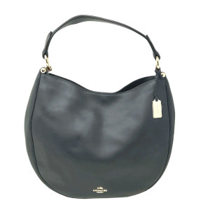This image presents a Coach Nomad Glovetanned Hobo Shoulder Handbag for ladies, crafted from smooth black leather. Positioned upright against a white backdrop, the bag is viewed from a slight angle, highlighting its curved shape. The handbag features a single shoulder strap, attached by gold hardware. A small tag adorns the strap on the right side, while the brand's logo is subtly displayed near the bottom center. The bag closes with a magnetic snap and includes an interior pocket with a zipper. The bag has slightly visible marks on the exterior shell due to storage. 