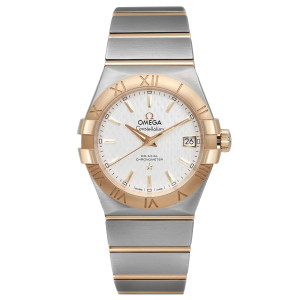 An image of a pre-owned OMEGA Constellation wristwatch in excellent condition displayed in a full frontal view. The watch has a round shape with a silver embossed lozenge dial, gold bezel, and a date indicator at the 3 o'clock position. It features luminous hands, stick indexes, and Roman numerals for 12-hour timekeeping. The band is a combination of stainless steel and yellow gold, presenting a luxury style unisex adult wristwatch. The watch is positioned centrally and photographed from the front at a close distance, providing a clear view of its design and features.