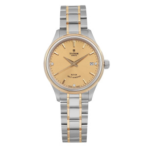 An image of a women's unworn TUDOR Style 34mm wristwatch taken from a front-facing angle at close distance. The watch features a two-tone stainless steel and gold bracelet and a champagne dial with a date indicator located at the 3 o'clock position. The watch hands and hour markers are clearly visible, highlighting the elegant design.