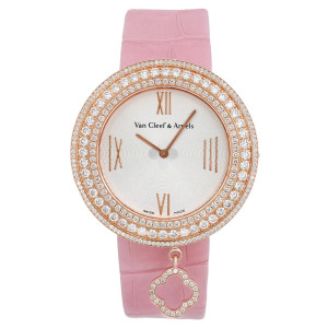An image of a pre-owned wristwatch in a front full frontal view. The watch features a pink strap and a round face adorned with two concentric rows of sparkling stones around the bezel. The dial is elegantly designed with Roman numerals and slender hands. A small, decorative charm hangs from the bottom of the watch face, adding a unique touch. The distance and angle are direct and centered, highlighting the watch's intricate details.