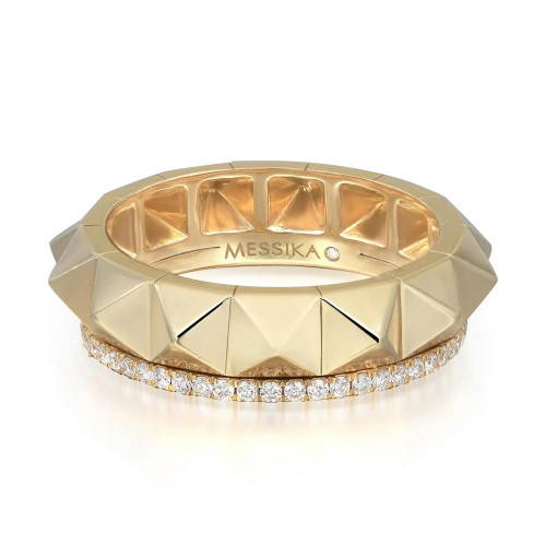 An image of a Messika women's Spiky Gatsby Diamond 18k yellow gold band ring, displayed in a close-up front view on a pure white background. The ring features a band of polished gold adorned with a circle of small, brilliant-cut diamonds set at the base. The brand name "MESSIKA" is prominently engraved on the top face of the ring. The design showcases geometric facets that give the ring a modern, sculptural look. The ring is centered and occupies a majority of the frame, providing a clear and detailed view of its design and craftsmanship.