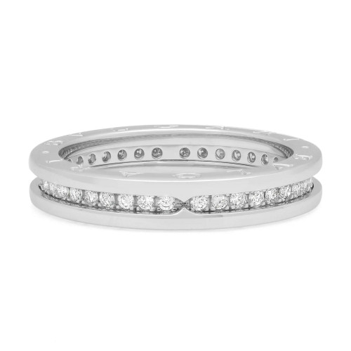 An image of a Bvlgari B.Zero1 one band 18k white gold unisex adult ring with pave diamonds, positioned centrally against a white background. The ring is viewed from a top-down angle that shows a full, unobstructed view of the diamonds and design. The image is taken from a close distance, allowing for details of the diamonds and the metal band to be clearly visible. The ring features a band where inside encrusted with small diamonds in a channel setting creating a luxurious and elegant appearance. The condition of the ring is new. 