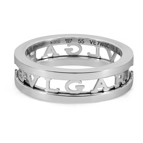 An image of a unisex adult Bvlgari B.Zero1 Openwork Logo Spiral one band ring without stones, showcased from a top angle to display the brand's signature engraving. The ring appears in a close-up view, centered in the frame with a slight tilt to emphasize the depth and details of the cut-out letters spelling "BVLGARI" around the band. The white gold polished surface reflects light, enhancing the visual texture and craftsmanship. The markings indicating the metal purity, designer logo, ring size, and serial number are visible on the inner surface, denoting authenticity and brand identity. The background is a neutral, light color providing contrast to the metallic sheen of the ring. The condition of the ring is new. 