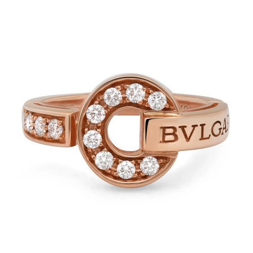 An image of a Bvlgari Bvlgari women's ring with diamonds, showcasing a close-up, angled view that highlights the 18k rose gold band and setting. The ring features a circular element at the center with the Bvlgari logo engraved on the side. Multiple sparkling diamonds are set around the circumference of the circle and along the band, catching the light. The background is white, emphasizing the ring's design and the brilliance of the diamonds.