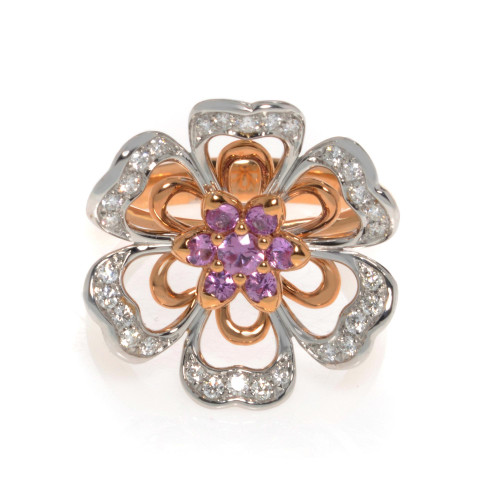 An image of new Luca Carati women's ring with diamonds and gemstones, shown in a close-up view directly from above. The ring features a flower design with rose gold petals and a cluster of pink sapphire gemstones at the center, surrounded by petals outlined with sparkling diamonds set in white gold. The intricate design is prominently displayed against a white background.