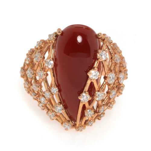 An image of a new Luca Carati women's cocktail ring featuring a large, pear shaped, central red Agate gemstone with a glossy finish, set in a rose gold band. The band is intricately designed with multiple small round diamonds encrusted around it, creating a sparkling halo effect in rose gold. The ring is photographed from a top-down perspective at close range, highlighting the gemstone's smooth surface and the surrounding diamonds' brilliance.