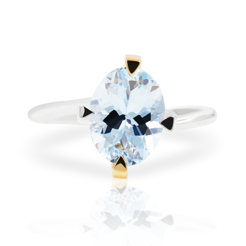 An image of a Comete Aquamarine two tone gold brand ring designed for women, featuring a prominent central aquamarine. The ring is displayed in a frontal view with a slight angle to show the oval aquamarine and the setting's design. The gemstone is mounted on a two tone gold band , and the image is taken from a close distance to highlight the ring's details. The background is white, emphasizing the ring's elegance and shine.