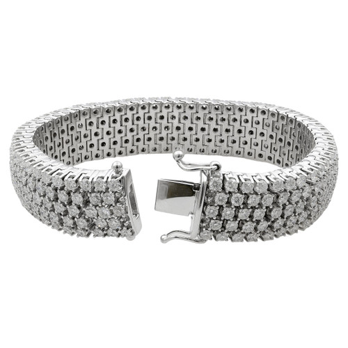 An image of a Rachel Koen women's white gold thick flexible diamond tennis bracelet with diamonds, displayed in a straight position with a slight bend, occupying the central part of the frame. The bracelet is shown from a top view at a close distance, allowing clear visibility of the intricate diamond details and the polished clasp mechanism on a neutral white background. The diamonds are set closely together, covering the entire surface of the bracelet, which reflects light to emphasize their sparkle and the bracelet's luxurious appearance.