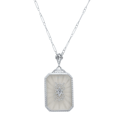 An image of a women's white gold necklace by Rachel Koen, featuring a pendant with intricate designs adorned with diamonds and clear crystal gemstones. The necklace is displayed at a slight angle, captured from a frontal view, highlighting the rectangular pendant with ornate detailing. The chain is visible, extending upwards from the pendant, and the image is taken from a close distance to emphasize the pendant's craftsmanship.Excellent pre-owned condition. 