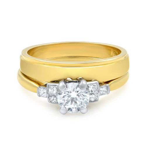 An image of a women's two piece engagement ring set by Rachel Koen, showcasing a front-facing view at a close distance. The ring features a central round diamond held by four prongs, flanked by smaller princess cut diamonds on a yellow gold band. The angle highlights the intricate detailing and sparkle of the diamonds. Excellent pre-owned condition. 