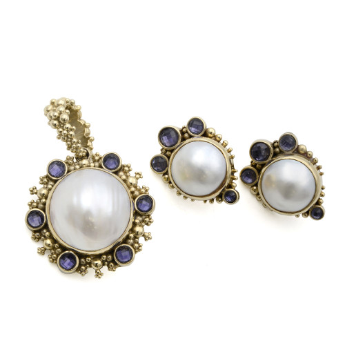 An image of a women's jewelry set by Stephen Dweck, featuring a pendant and matching earrings. The set is designed with large central pearls surrounded by small yellow gold beads and amethyst. The pendant is positioned on the left, slightly angled to the right, while the earrings are placed side by side on the right, at a slight angle to each other. The image is taken from a direct overhead perspective, focusing closely on the intricate details of the pieces.Its excellent pre-owned condition. 