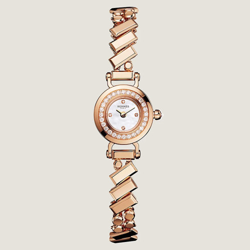 An image of a pre-owned HERMÈS  Faubourg Polka 15mm 18K Rose Gold MOP Diamond Lady's Watch W054184WW00 taken from a straight-on angle, displaying the watch face and intricate bracelet design. The watch features a round face with a mother-of-pearl dial surrounded by a diamond-encrusted bezel. The bracelet is composed of geometrically shaped links, creating a sophisticated and elegant look. The image is captured from a close distance, showcasing the luxurious details and craftsmanship of the timepiece.