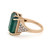 An image of a women's Rachel Koen brand cocktail ring with diamonds and emerald, displayed at a slight angle to show the profile and top view. A large, emerald-cut green emerald is the centerpiece, set in a yellow gold band. The band splits near the top, with one side adorned with a triangle of pave-set diamonds. The ring is captured in close-up, with a focus on the intricate details and the contrast between the sparkling diamonds and the deep green emerald.The condition of the ring is pre owned. 