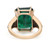 An image of a Rachel Koen women's cocktail ring with a large, central emerald-cut emerald in a rich green color, flanked by triangular diamond accents, set in a polished yellow gold band. The ring is photographed from a top-down angle at close distance from the back, showcasing the gemstone's facets and the diamonds' placement within the setting.The condition of the ring is pre owned. 