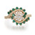 An image of a Rachel Koen women's ring with diamonds and green emeralds. The ring is photographed from a top-down perspective at a close distance, showcasing the intricate design. A cluster of sparkling diamonds is set at the center, surrounded by a halo of green emeralds. The band, made of polished 14k yellow gold, elegantly curves around the gemstone arrangement, suggesting movement and a fluid design. The lighting emphasizes the brilliance of the diamonds and the rich color of the gemstones.