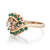 An image of a Rachel Koen women's ring featuring diamonds and green emeralds. The ring is displayed at a three-quarter angle showing the band and setting in detail, with a clear view of the multiple diamonds and green emeralds embedded in the 14k yellow gold setting. The photo is taken from a close distance, focusing on the left side of the ring, highlighting the intricate design and the contrast between the sparkling diamonds and the rich green emeralds.