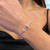 An image of a Messika diamond bracelet for women, gracefully worn on a wrist. The bracelet features two prominent diamond-encrusted triangles facing away from each other. The photo is taken at a close distance, focusing on the bracelet at a slightly angled side view, which highlights the sparkling diamonds and the elegant design of the piece against the backdrop of the wearer's skin.