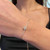 An image of a Messika diamond bracelet for women, worn on the wrist. The bracelet features a delicate chain with a circular diamond-encrusted centerpiece. The photo is taken at a close-up angle, focusing on the bracelet as it rests against the skin, with a blurred background emphasizing the jewelry's details.