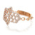 An image of a women's Messika brand ring with diamonds, featuring a close-up side view on a white background. The ring is angled slightly to the left, with the band visible in the foreground and the intricately designed diamond-encrusted portion positioned at the center. The ornate design suggests multiple interlocking shapes, all lavishly decorated with small, round, brilliant-cut diamonds that catch the light. The band appears to be made of polished rose gold, and the overall distance from the camera provides a clear view of the ring's details.