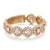 An image of a luxurious Messika women's ring with diamonds, displayed at a slight angle to showcase the intricate design. The ring features a series of connected oval shapes, each encrusted with multiple sparkling diamonds set in a warm, rose gold band. The band has a polished finish with hallmarks visible, and the diamonds catch the light beautifully. The photo is taken from a close distance, highlighting the ring's detailed craftsmanship and the brilliance of the stones.