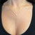 An image of a Messika brand women's necklace with diamonds, worn at a close distance to the camera. The necklace features a delicate rose gold chain with evenly spaced diamonds leading to a central, larger, triangle-shaped diamond pendant. From this pendant, a vertical drop chain with additional diamonds extends down the chest. The photo is taken from a front-facing angle, emphasizing the sparkle and design of the diamonds against the skin.