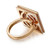 An image of a women's Messika brand Spiky Diamond cocktail ring, captured from a high angle showing the ring at a slight tilt with the band in the foreground. The ring features a polished gold band with the name "MESSIKA" engraved, and an intricate, geometric design adorned with sparkling diamonds set into the top section which is prominently displayed. The gold exhibits a warm tone, and the diamonds provide a contrast with their bright sparkle. The image is shot up close, emphasizing the detail and craftsmanship of the ring.