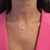 An image of a Messika women's Glam'Azone chain necklace with diamonds, centered and close-up on a model's neck. The necklace features a delicate chain with a prominent diamond pendant, showcased against the backdrop of a pink garment. The view is straight-on, with the necklace positioned horizontally across the neck, providing a clear view of its design and sparkle.